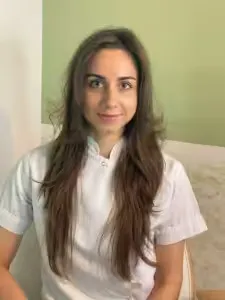 Lächelnde Frau in weißem Hemd vor grüner Wand