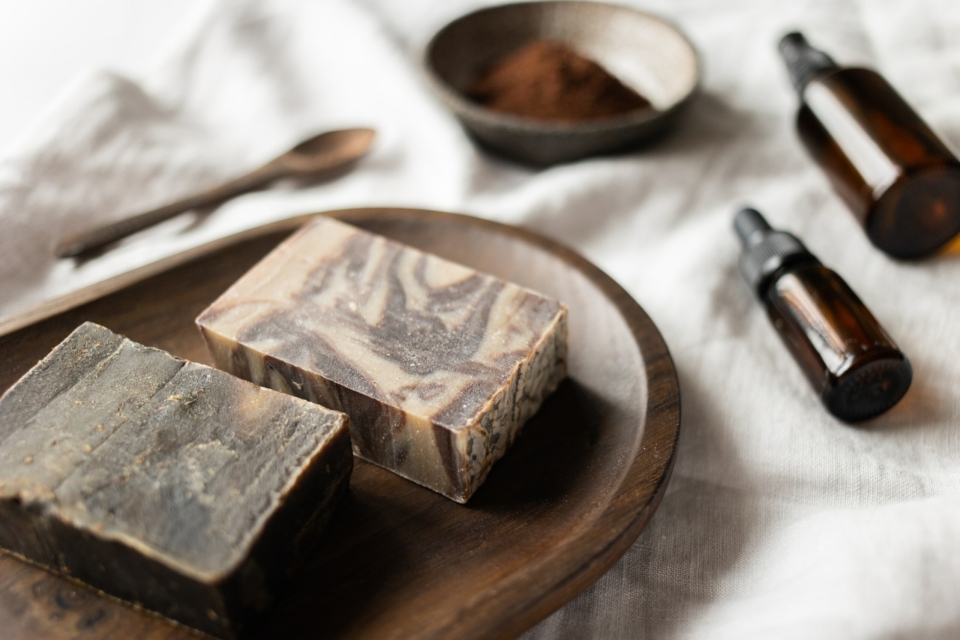 Handmade brown soap on timber board near aromatic oil