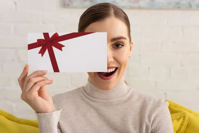 Woman holds gift card in front of face.