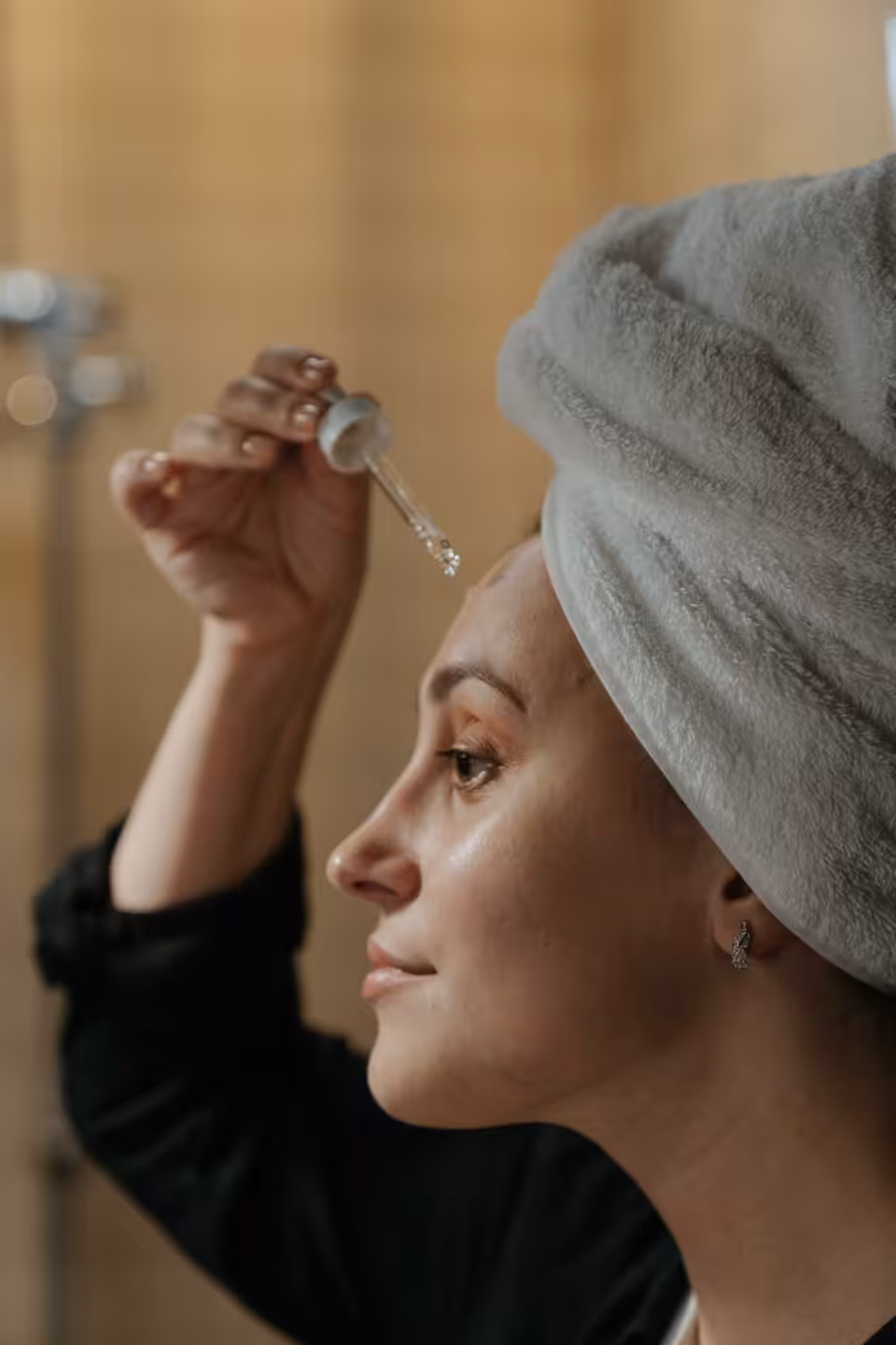 Woman drips a serum onto her forehead